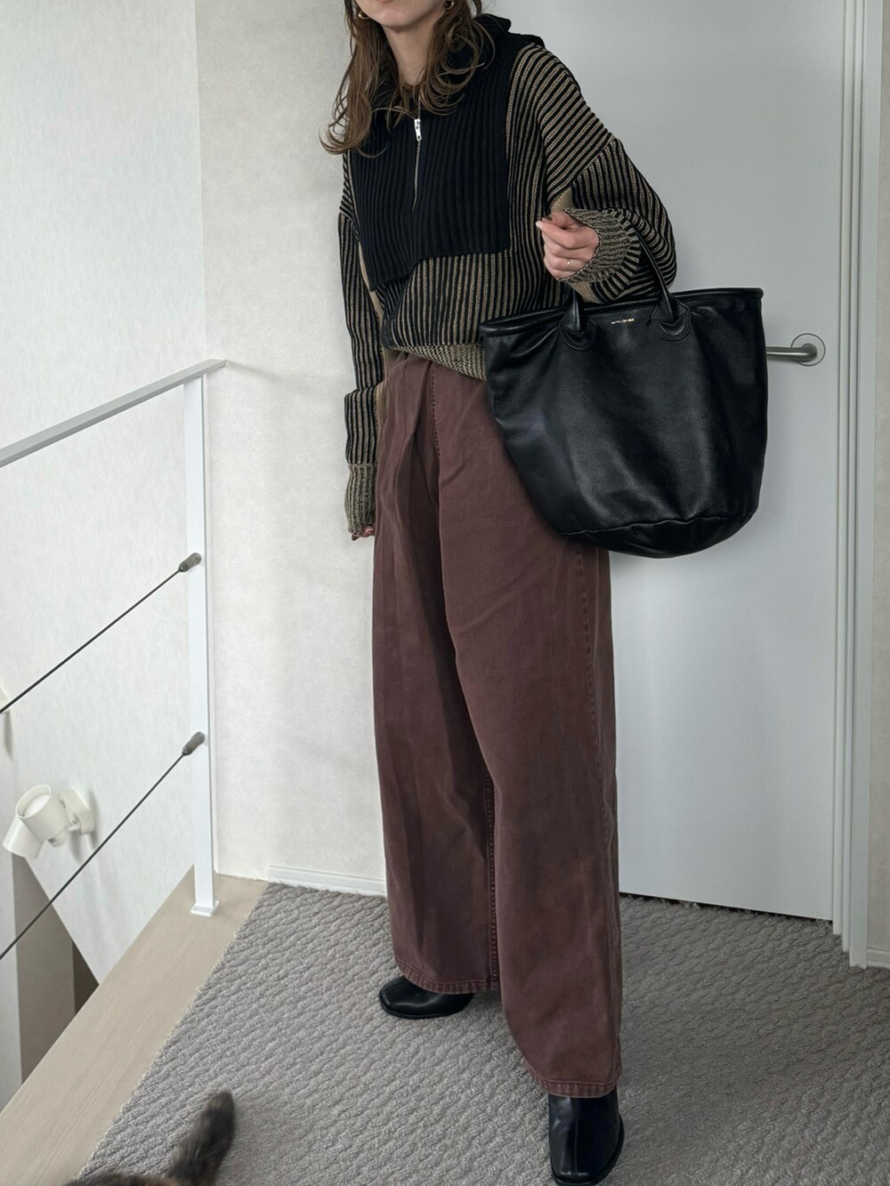 ブラック系のニット/セーター、ブラウン系のデニムパンツ、ブラック系のトートバッグを着用したレディースの冬コーディネートの4枚目の写真