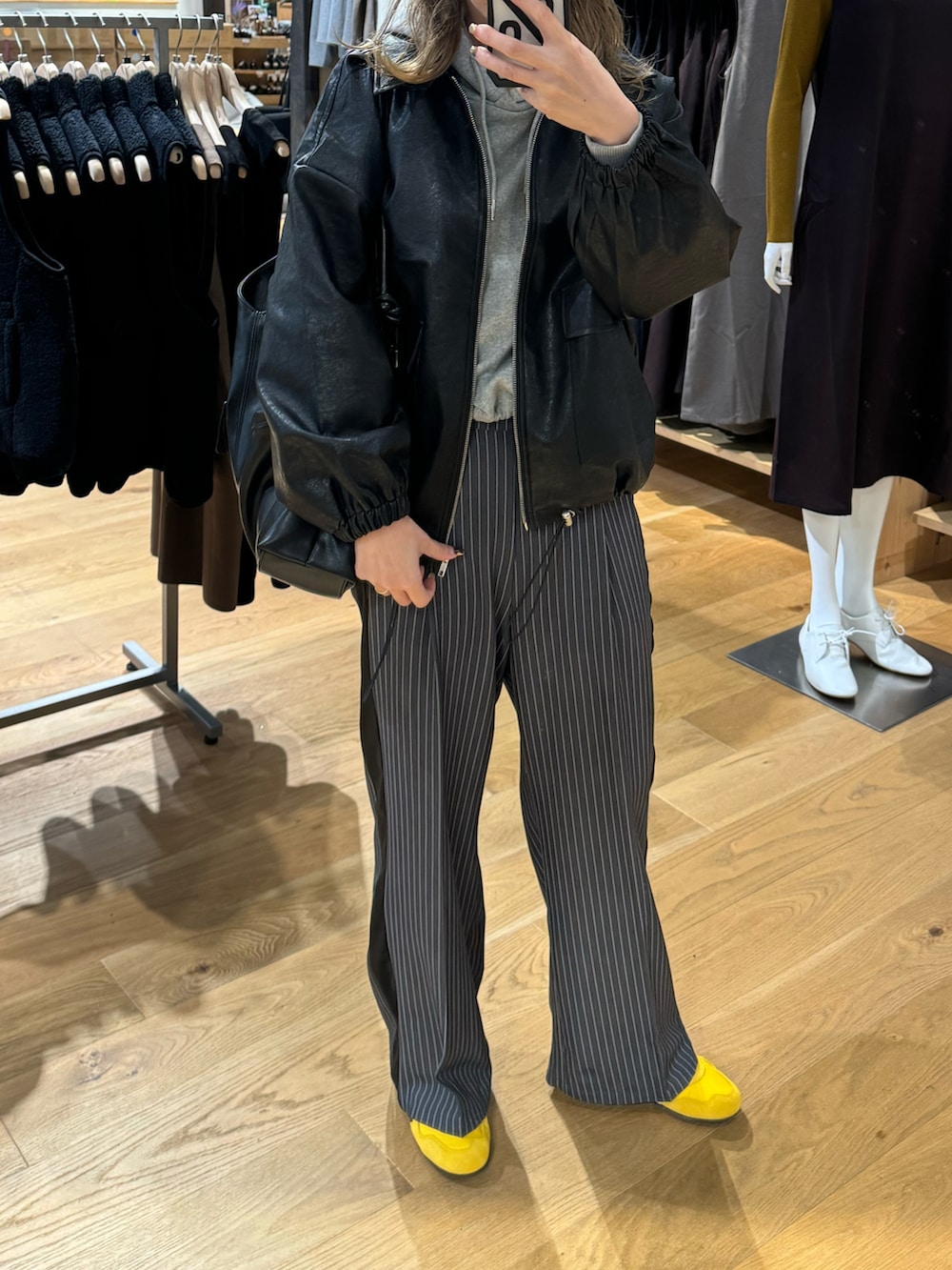 ブラック系のブルゾン、グレー系のスラックス、イエロー系のスニーカーを着用したレディースの秋コーディネートの3枚目の写真