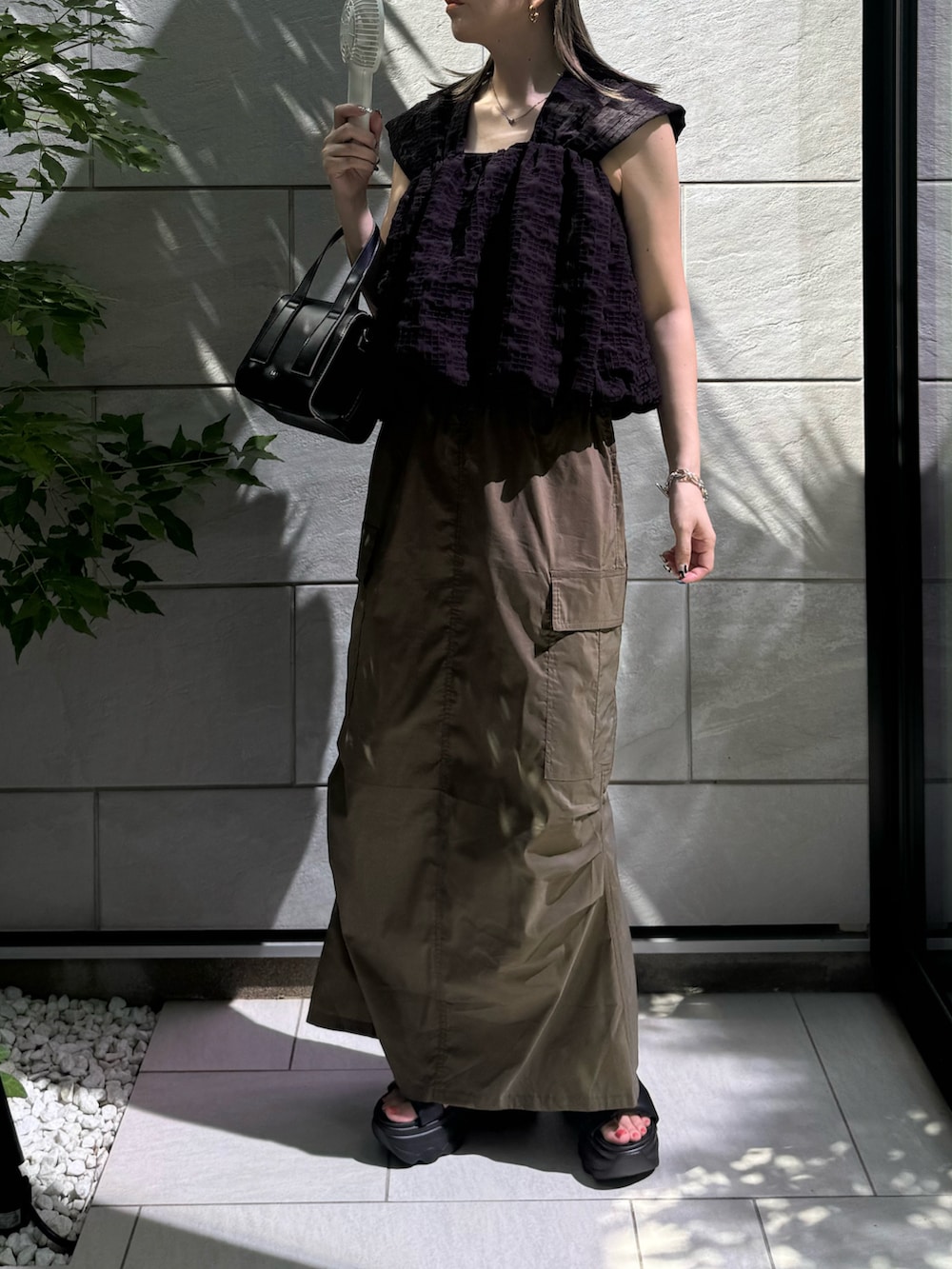 ブラック系のその他トップス、グリーン系のスカート、ブラック系のサンダルを着用したレディースの夏コーディネートの5枚目の写真