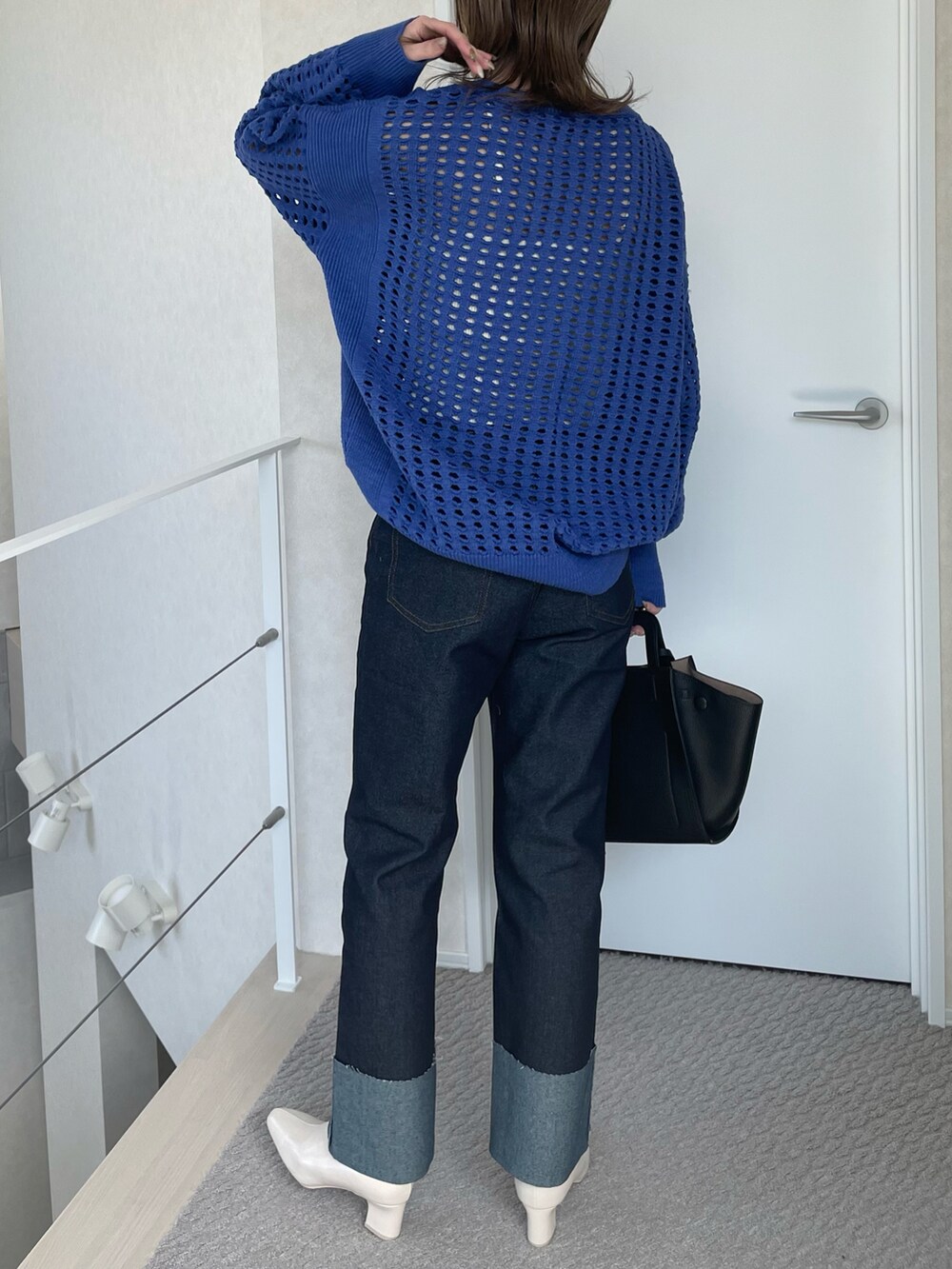 ブルー系のデニムパンツ、ブルー系のニット/セーター、ブラック系のハンドバッグを着用したレディースの春コーディネートの3枚目の写真