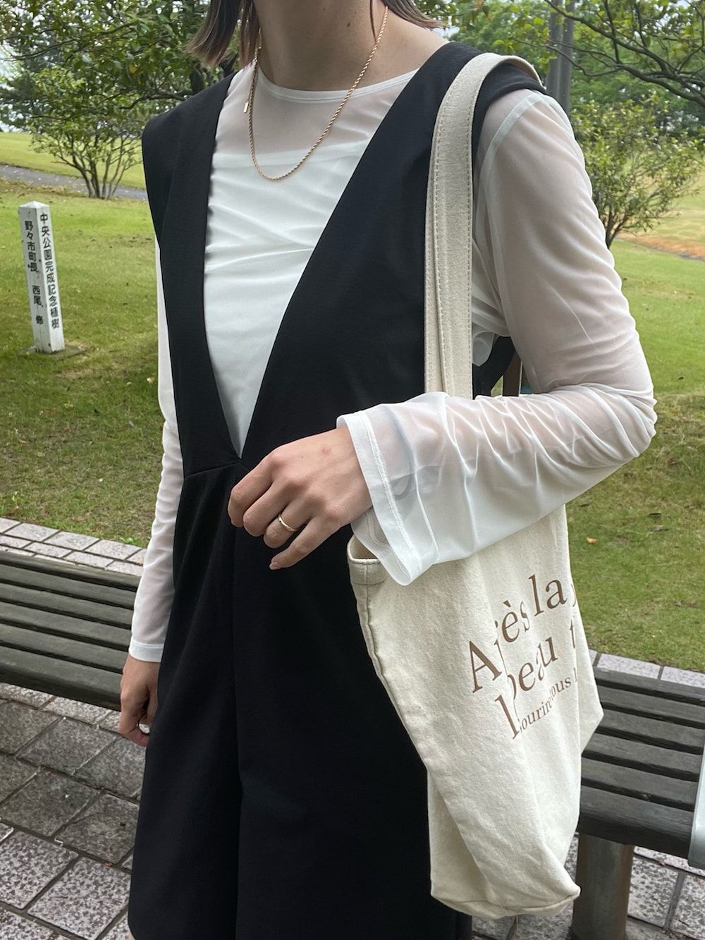 ブラック系のサロペット/オーバーオール、ホワイト系のTシャツ/カットソー、ホワイト系のサンダルを着用したレディースの春コーディネートの5枚目の写真