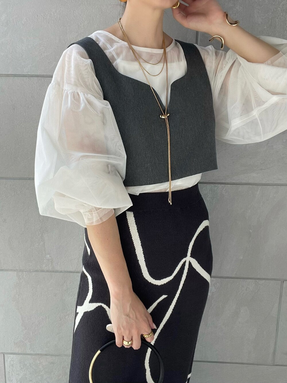 グレー系のスカート、ホワイト系のシャツ/ブラウス、ブラック系のハンドバッグを着用したレディースの夏コーディネートの2枚目の写真