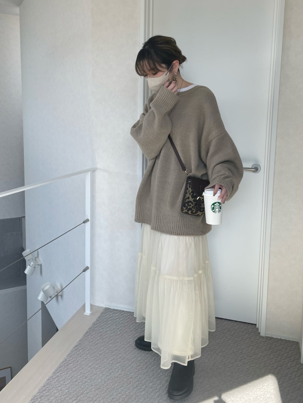 ベージュ系のカーディガン/ボレロ、ホワイト系のスカート、ブラウン系のショルダーバッグを着用したレディースの冬コーディネートの3枚目の写真