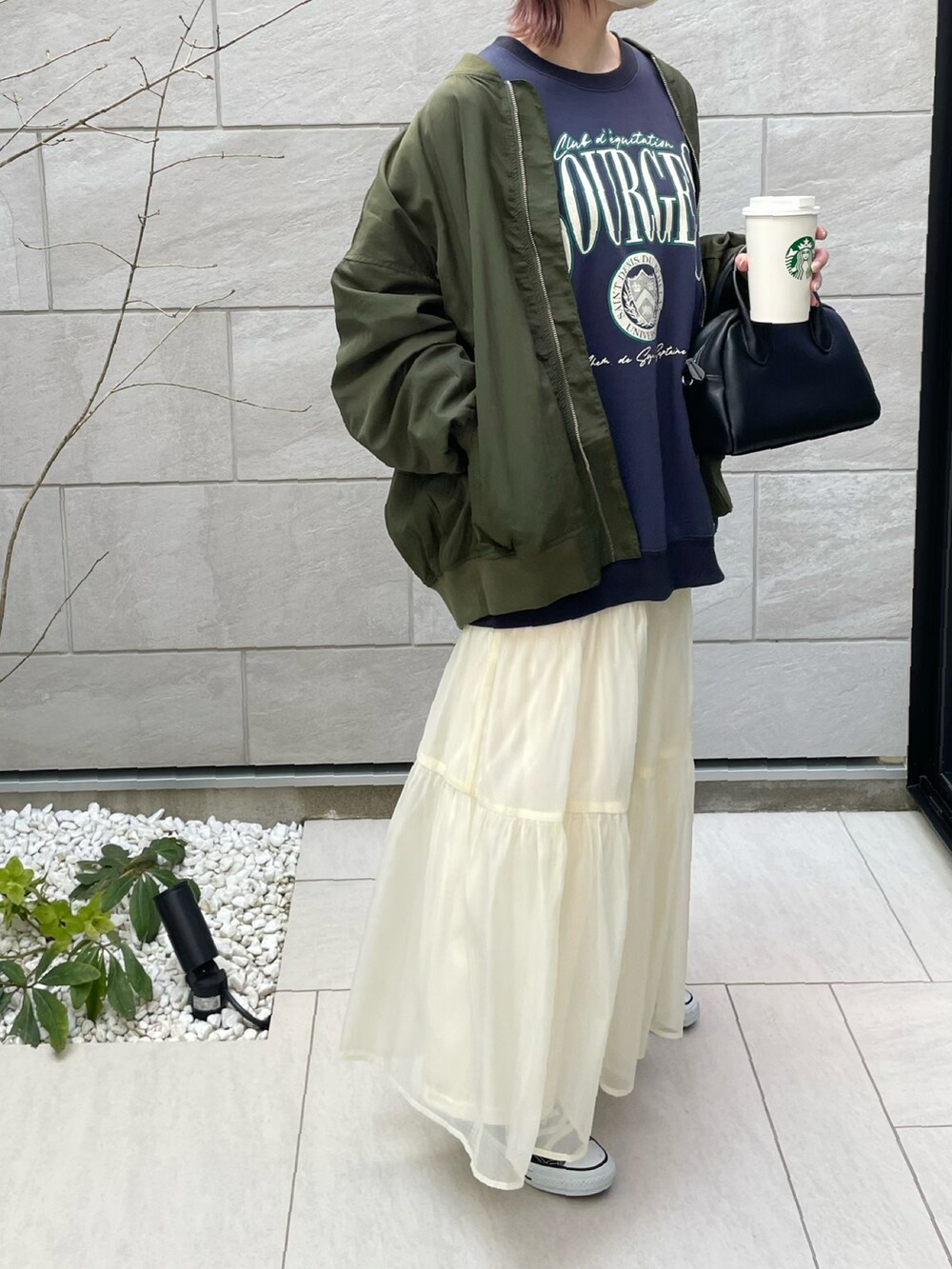 グリーン系のブルゾン、ホワイト系のスカート、ブルー系のスウェットを着用したレディースの春コーディネートの3枚目の写真