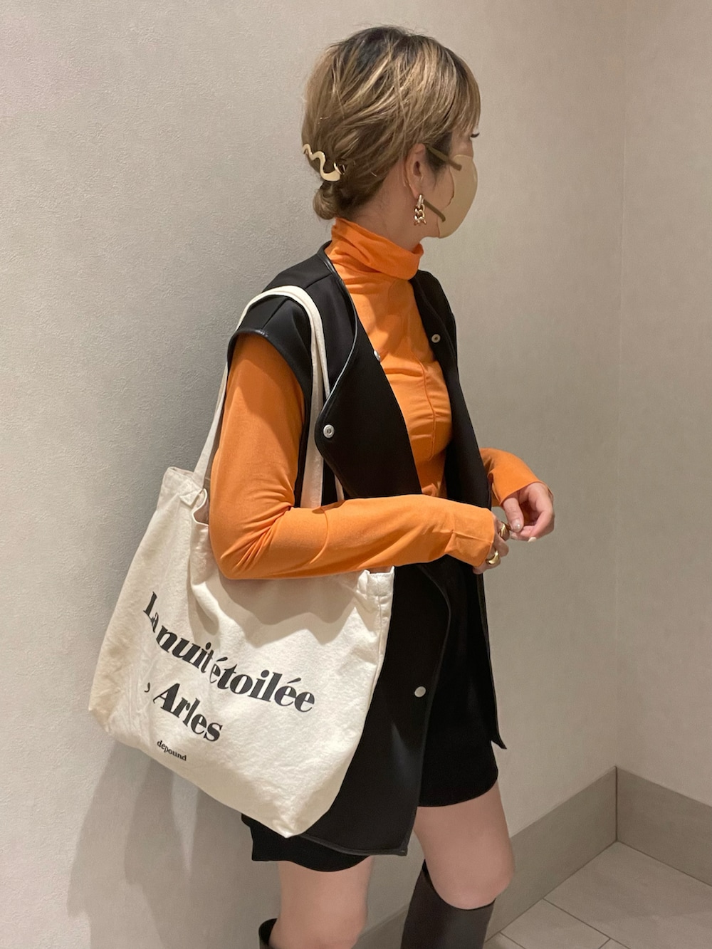 オレンジ系のTシャツ/カットソー、ブラック系のベスト、ブラウン系のブーツを着用したレディースの夏コーディネートの3枚目の写真