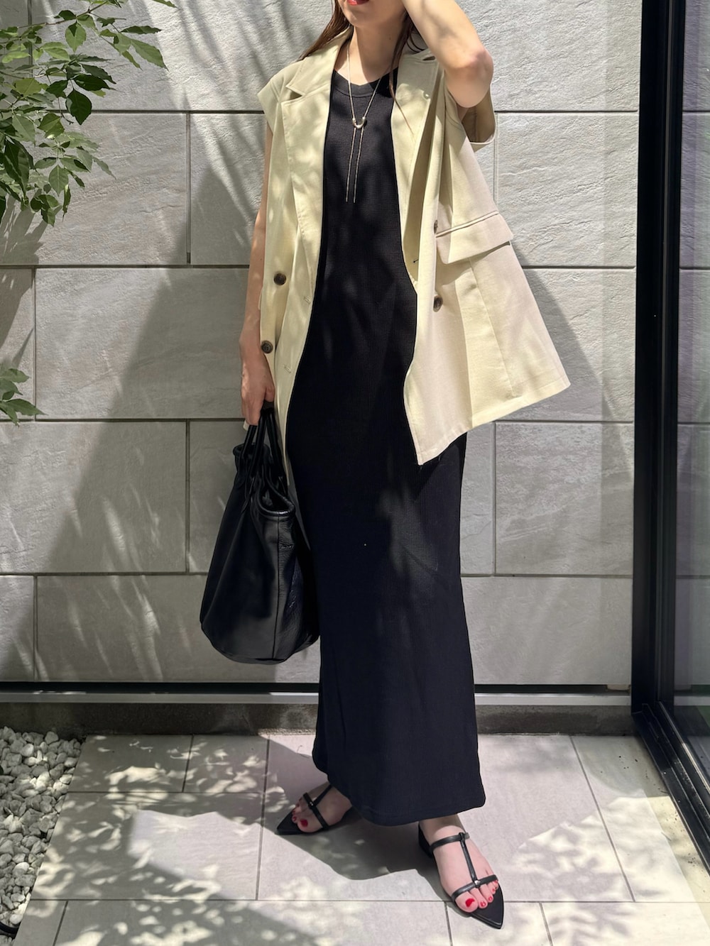 ブラック系のワンピース、ブラック系のサンダル、ホワイト系のベストを着用したレディースの夏コーディネートの2枚目の写真