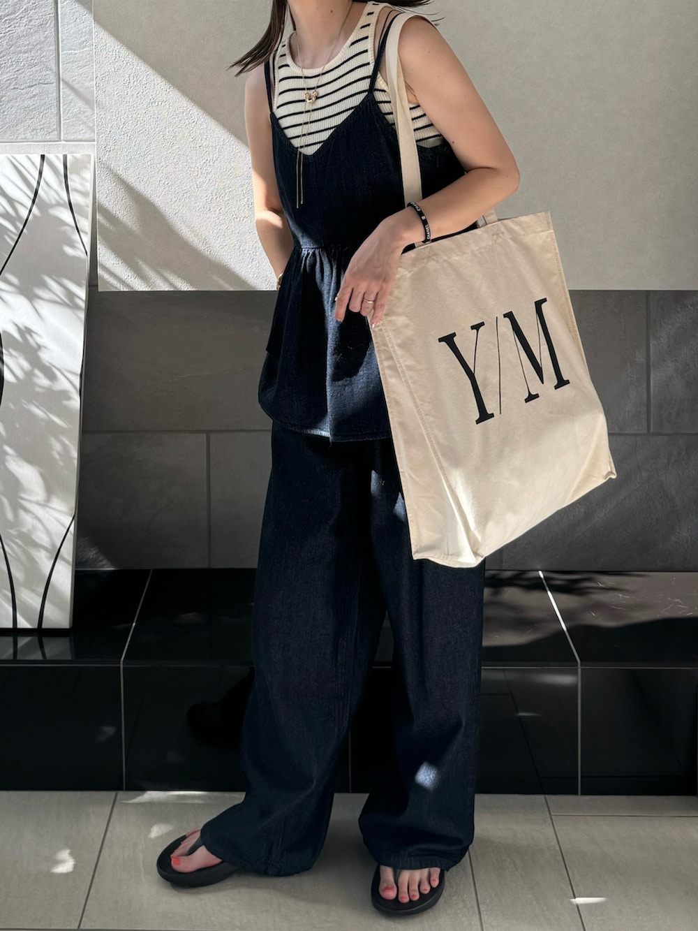 ブルー系のキャミソール、ブルー系のデニムパンツ、ホワイト系のトートバッグを着用したレディースの夏コーディネートの4枚目の写真