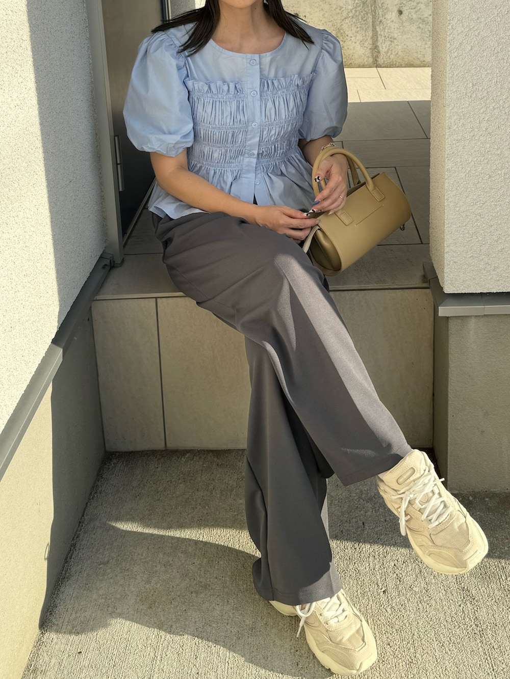 ブルー系のシャツ/ブラウス、グレー系のスラックス、ベージュ系のハンドバッグを着用したレディースの夏コーディネートの2枚目の写真