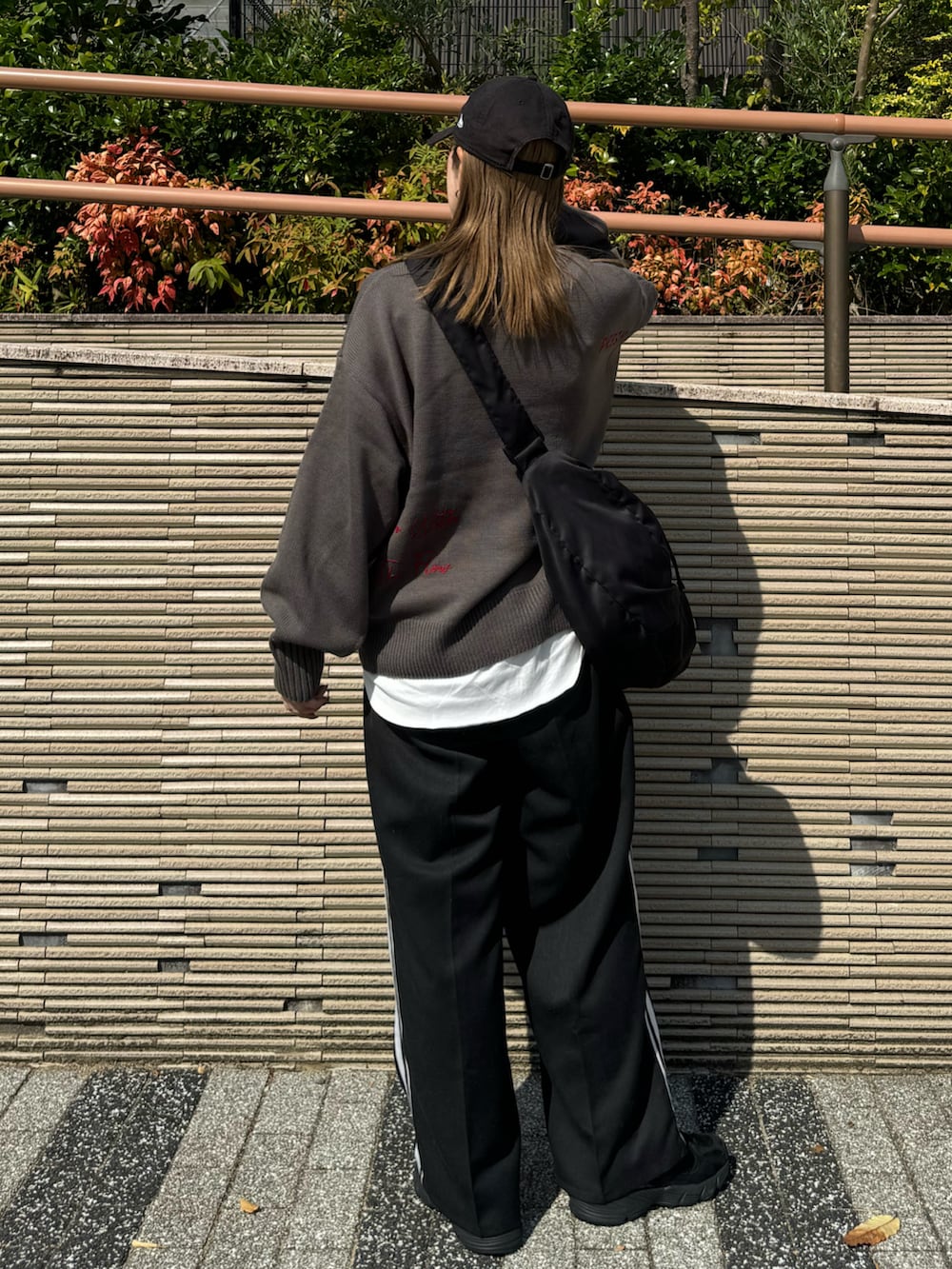 グレー系のニット/セーター、ブラック系のショルダーバッグ、ブラック系のスラックスを着用したレディースの秋コーディネートの5枚目の写真