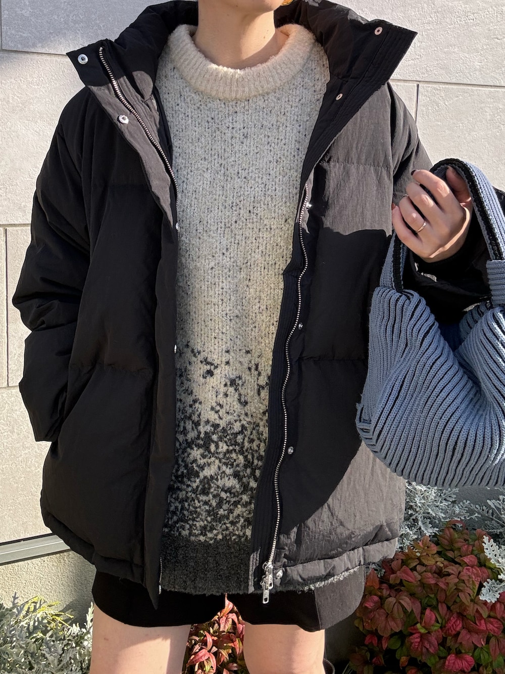 ブラック系のダウンジャケット/コート、ホワイト系のニット/セーター、ブルー系のハンドバッグを着用したレディースの冬コーディネートの5枚目の写真