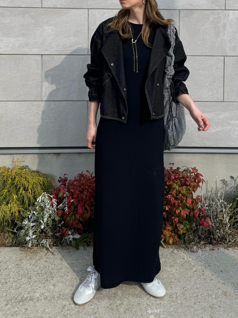 グレー系のスニーカー、ブラック系のワンピース、ブラック系のデニムジャケットを着用したレディースの春コーディネートの4枚目の写真