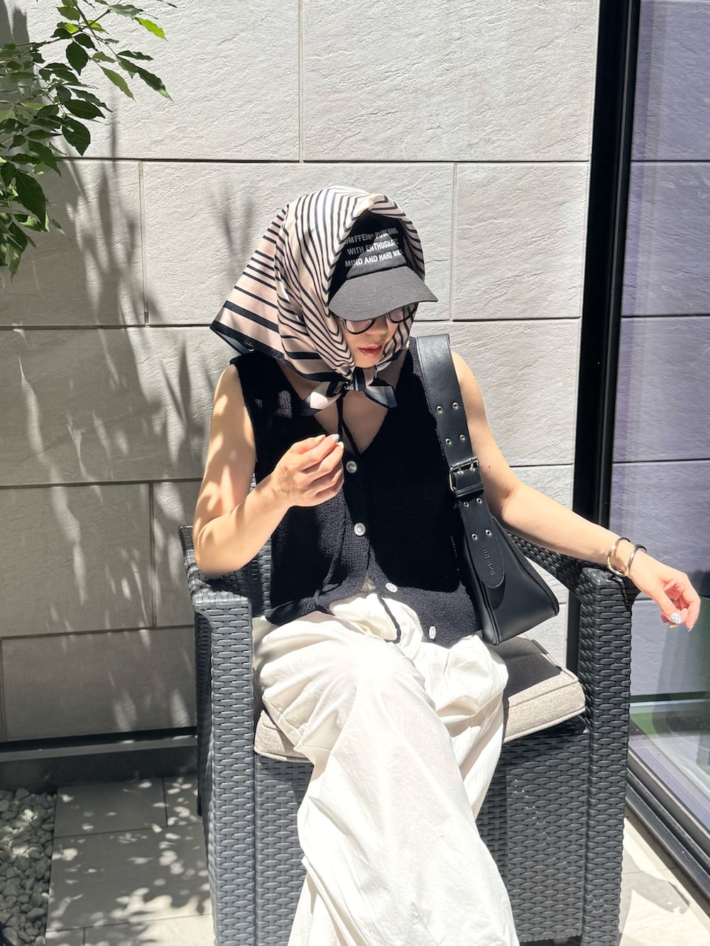 ブラック系のベスト、ブラック系のハンドバッグ、ホワイト系のその他パンツを着用したレディースの夏コーディネートの2枚目の写真