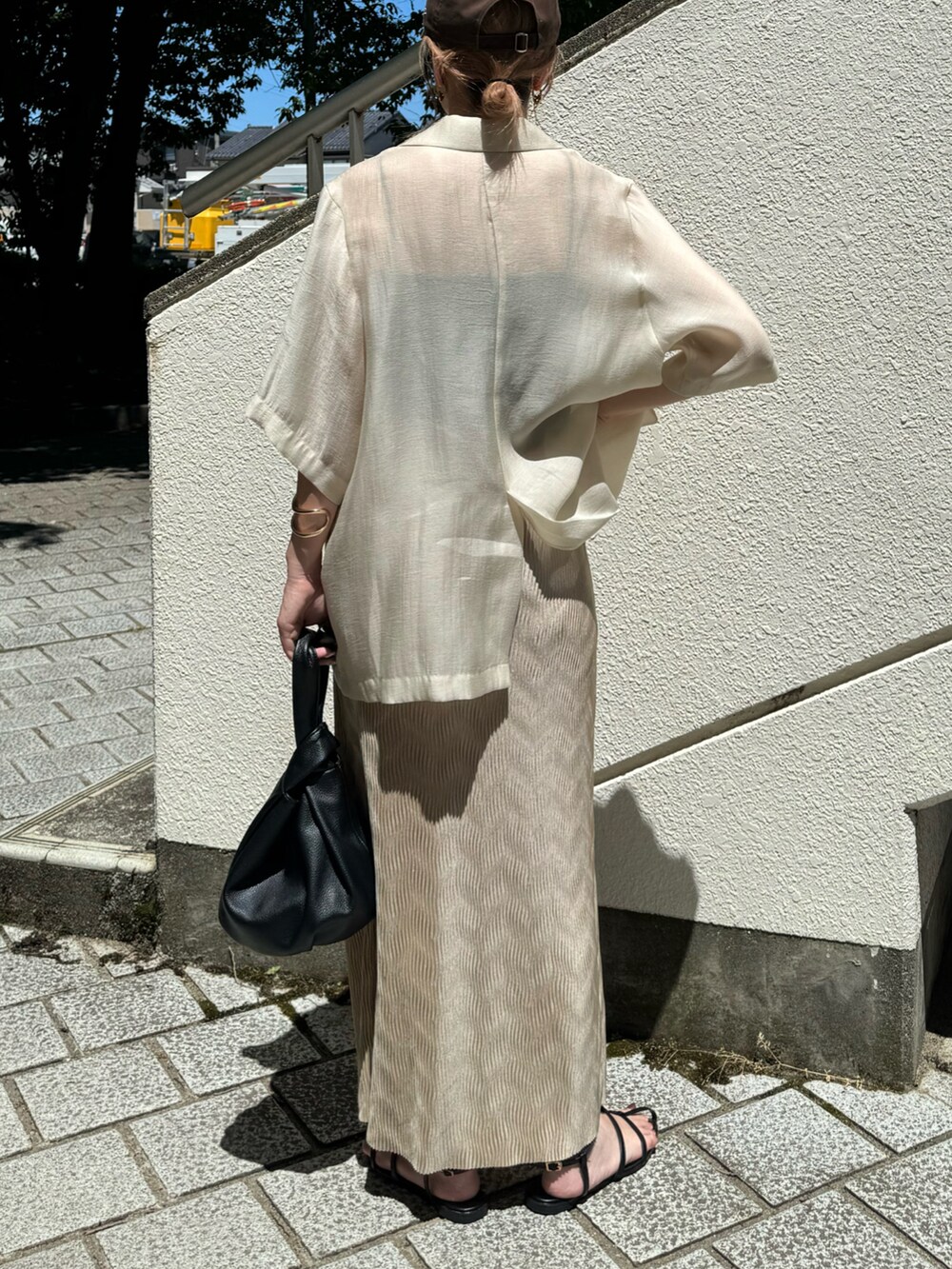 ホワイト系のテーラードジャケット、ブラック系のサンダル、ブラック系のハンドバッグを着用したレディースの夏コーディネートの3枚目の写真