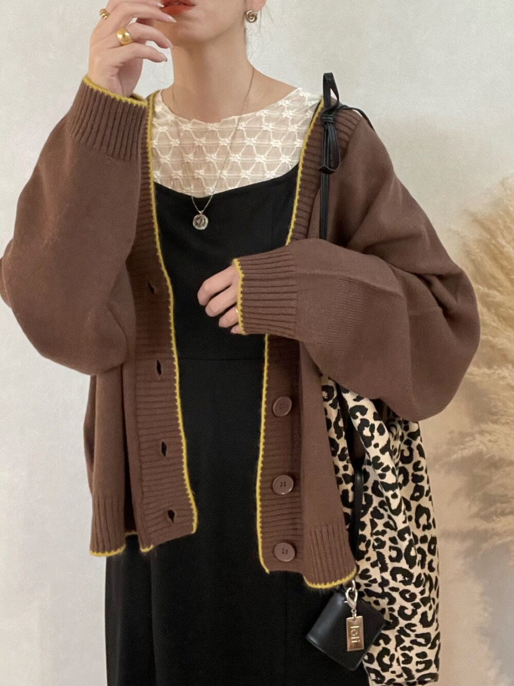 ブラウン系のカーディガン/ボレロ、ブラック系のワンピース、ホワイト系のブーツを着用したレディースの冬コーディネートの3枚目の写真