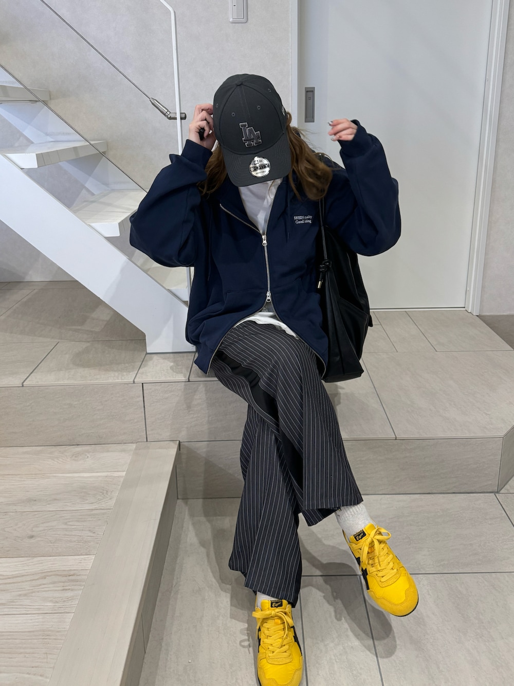 ブルー系のパーカー、グレー系のスラックス、イエロー系のスニーカーを着用したレディースの冬コーディネートの5枚目の写真