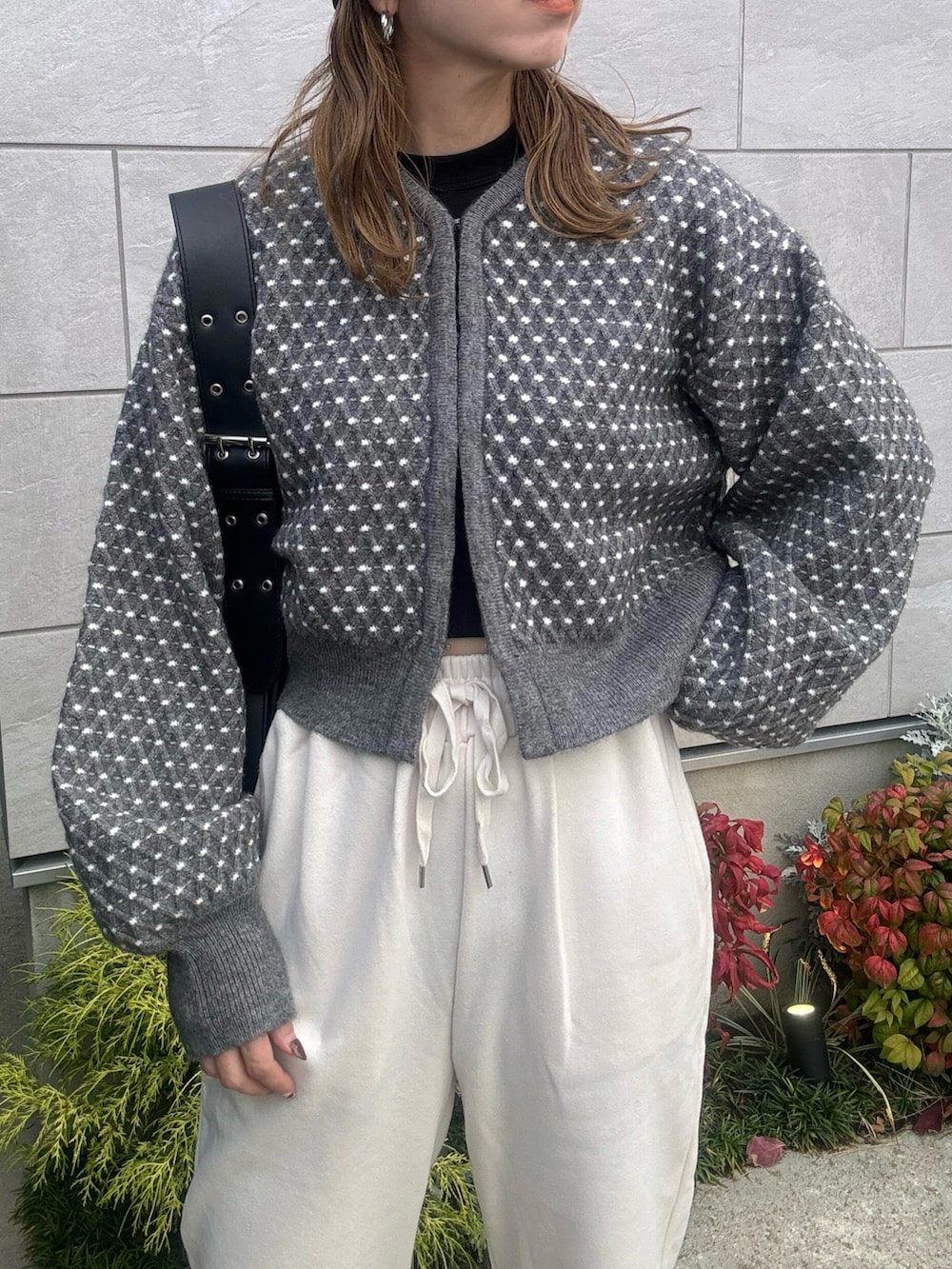 グレー系のニット/セーター、ブラック系のハンドバッグ、ブラック系のブーツを着用したレディースの秋コーディネートの4枚目の写真