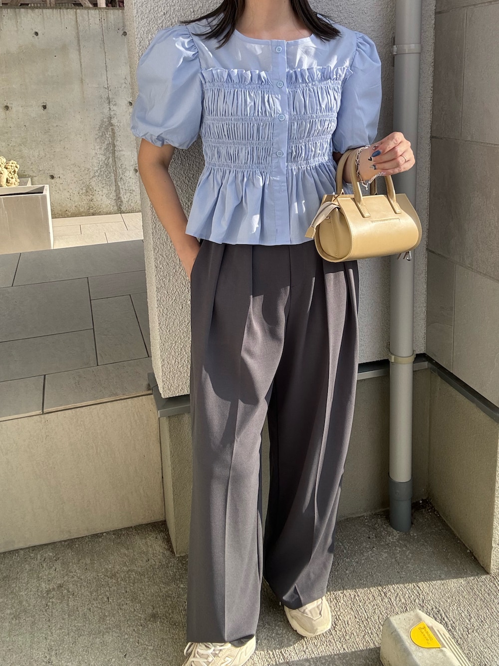 ブルー系のシャツ/ブラウス、グレー系のスラックス、ベージュ系のハンドバッグを着用したレディースの夏コーディネートの3枚目の写真
