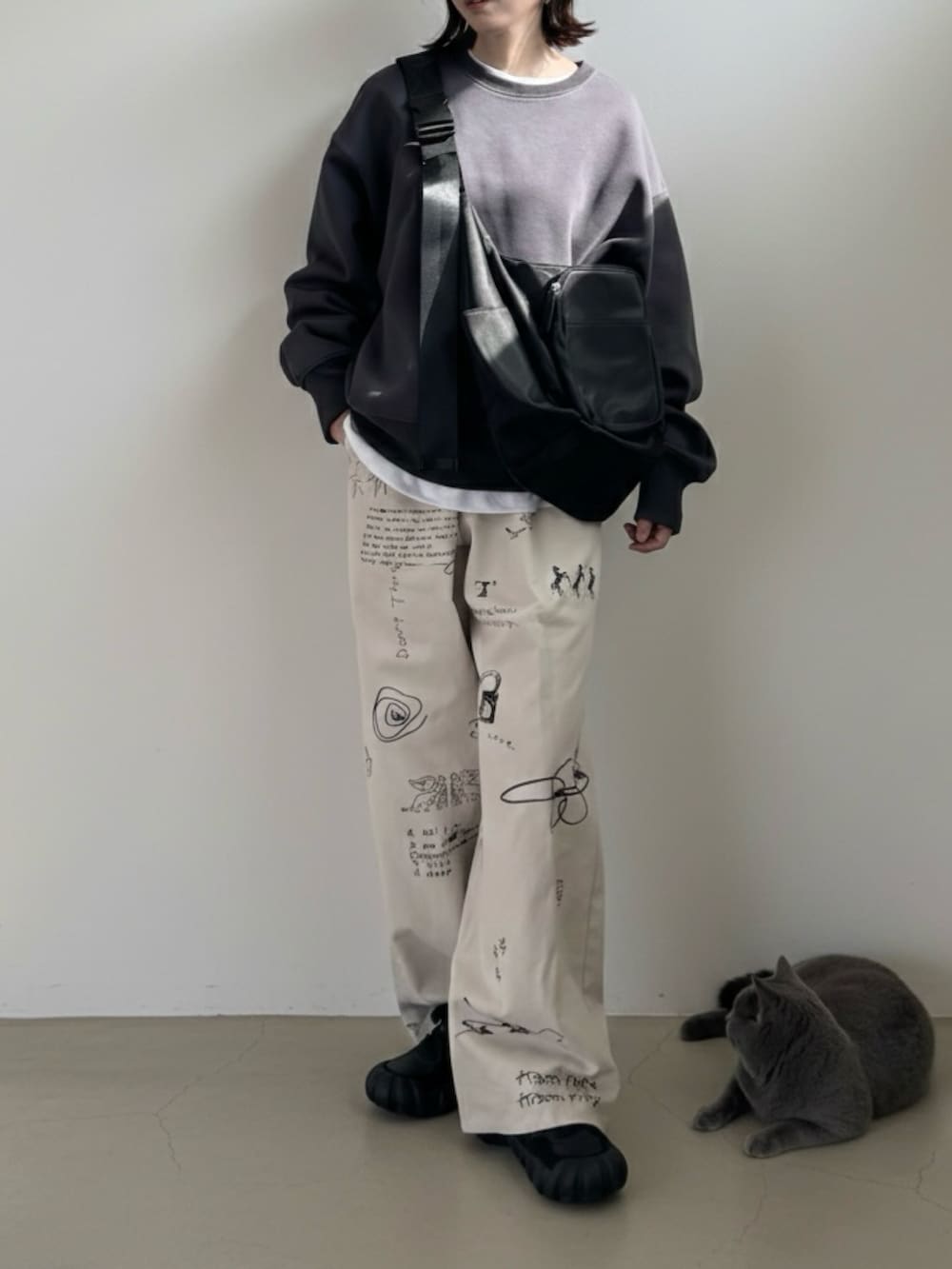 グレー系のスウェット、ブラック系のショルダーバッグ、ブラック系のスニーカーを着用したレディースの冬コーディネートの2枚目の写真