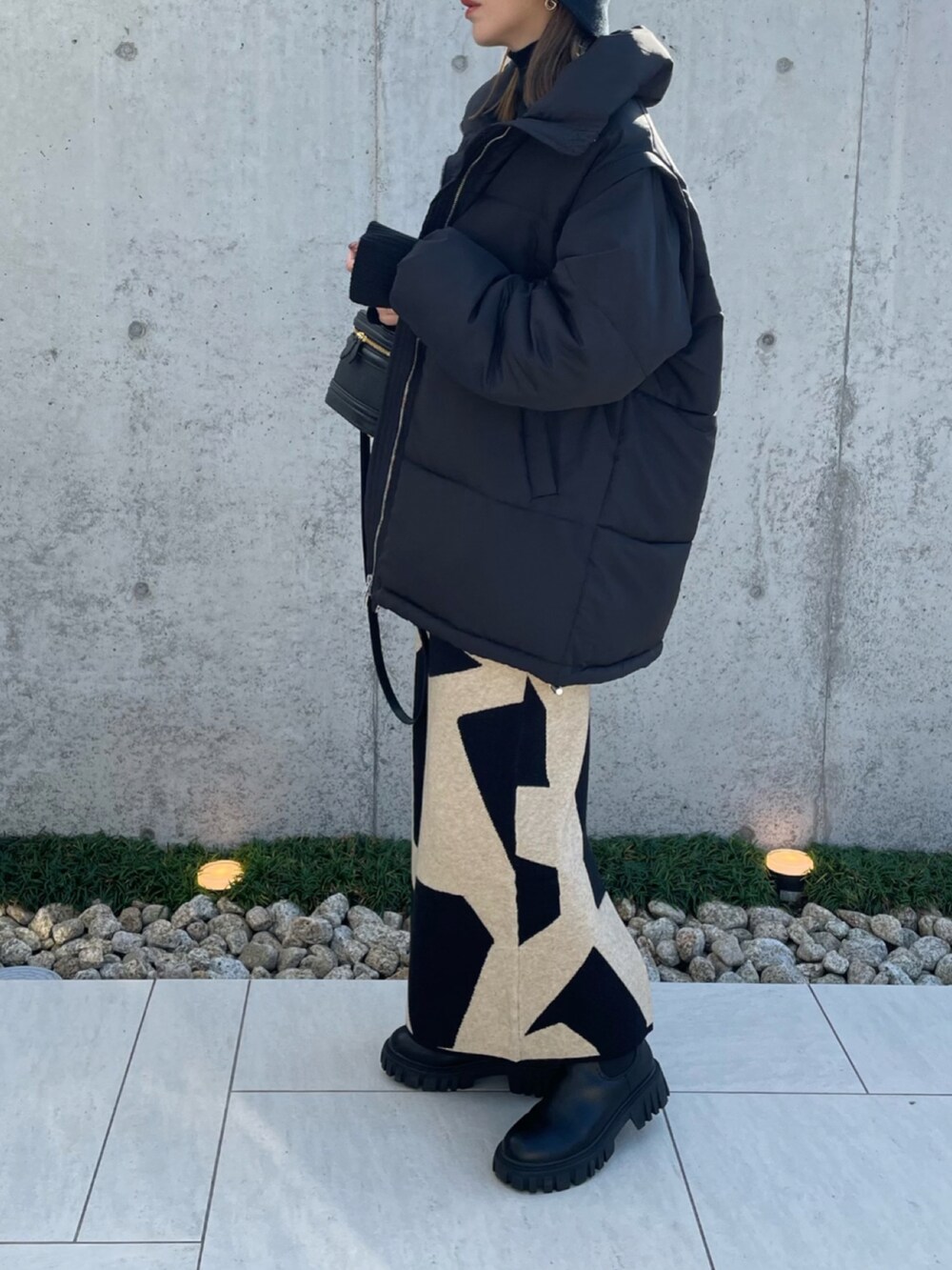 ブラック系のダウンジャケット/コート、ブラック系のブーツ、ブラック系のニット/セーターを着用したレディースの秋コーディネートの3枚目の写真