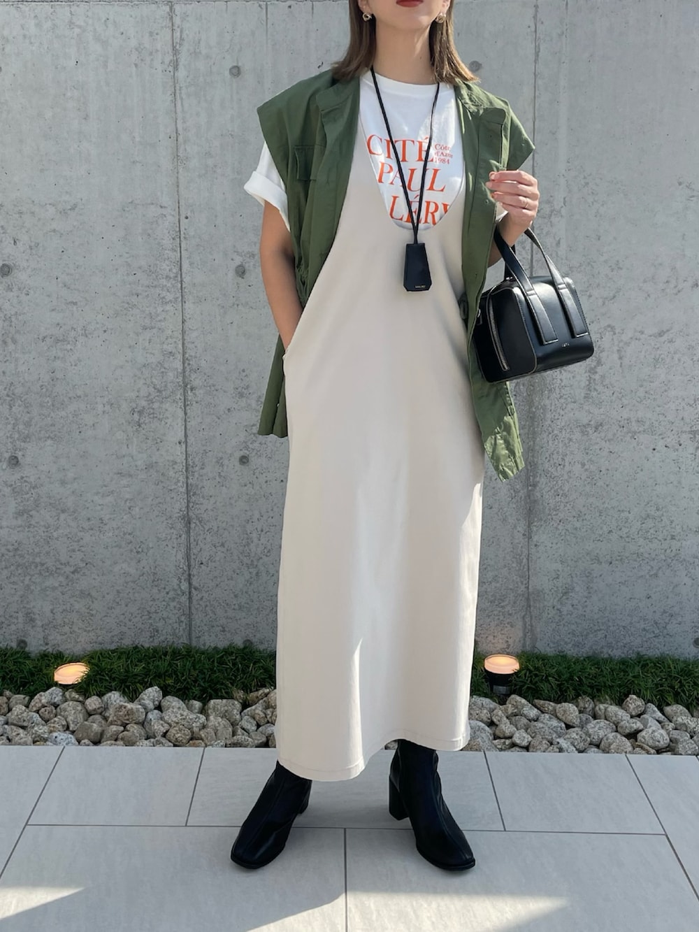 ブラック系のブーツ、ベージュ系のジャンパースカート、ブラック系のボストンバッグを着用したレディースの秋コーディネートの2枚目の写真