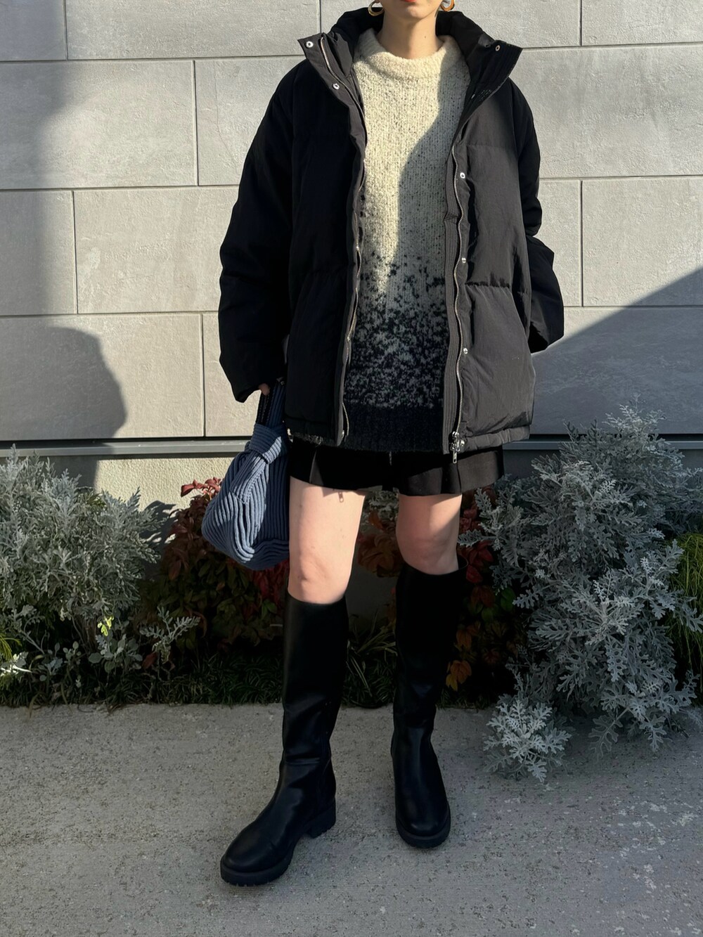 ブラック系のダウンジャケット/コート、ホワイト系のニット/セーター、ブルー系のハンドバッグを着用したレディースの冬コーディネートの3枚目の写真