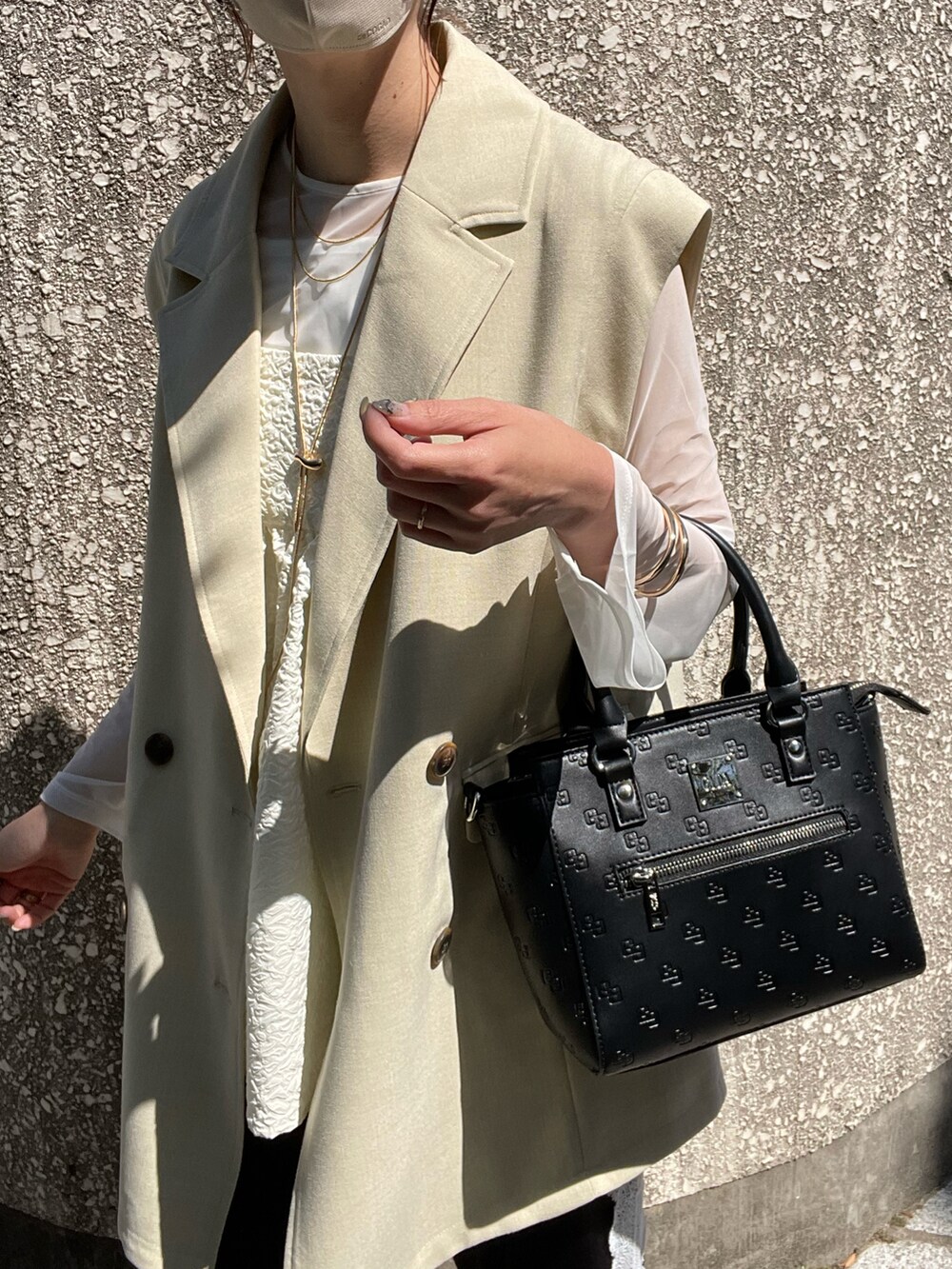 ブラック系のハンドバッグ、ホワイト系のTシャツ/カットソー、ホワイト系のベストを着用したレディースの春コーディネートの5枚目の写真