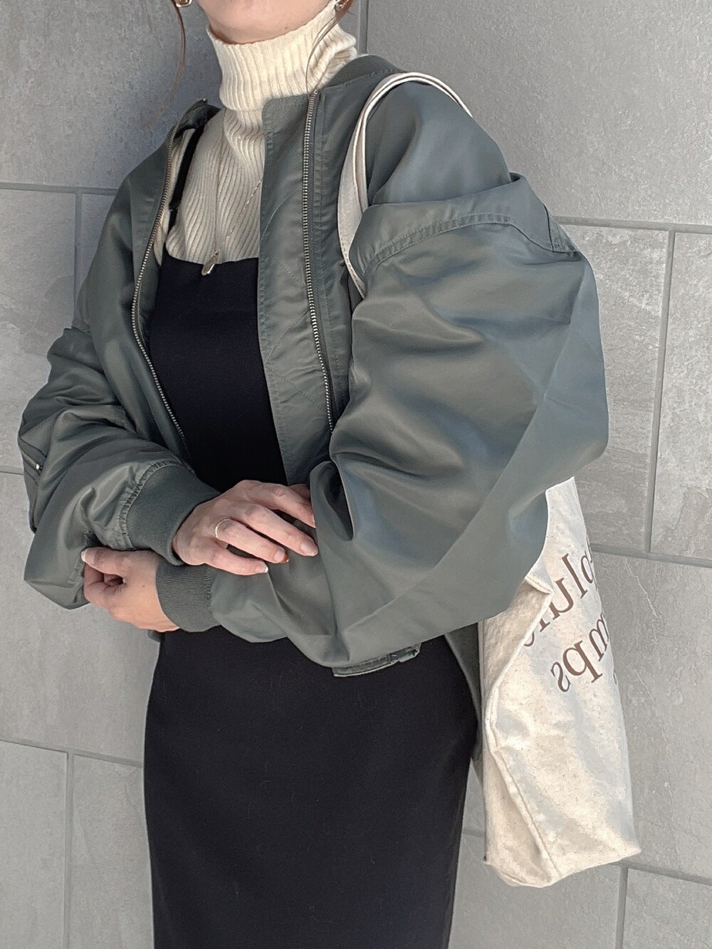 グリーン系のブルゾン、ホワイト系のニット/セーター、ブラック系のブーツを着用したレディースの秋コーディネートの5枚目の写真