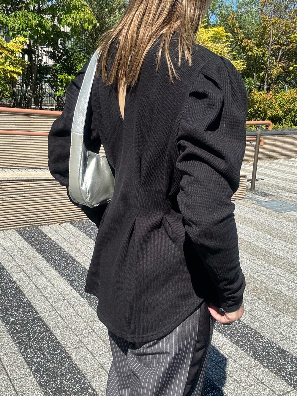 ブラック系のTシャツ/カットソー、シルバー系のショルダーバッグ、グレー系のスラックスを着用したレディースの秋コーディネートの5枚目の写真