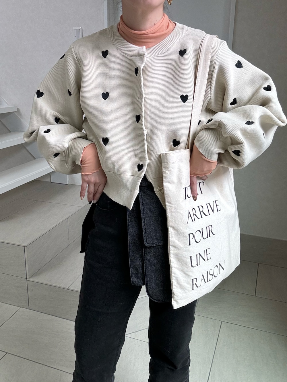 ベージュ系のカーディガン/ボレロ、ブラック系のデニムパンツ、オレンジ系のTシャツ/カットソーを着用したレディースの春コーディネートの4枚目の写真