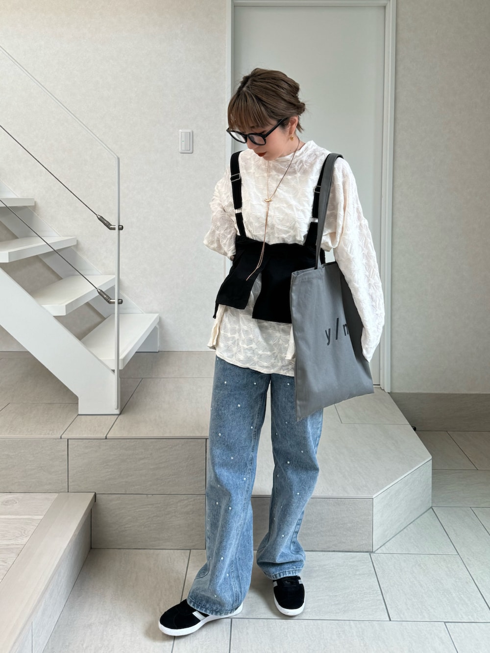 ホワイト系のTシャツ/カットソー、グレー系のトートバッグ、ブルー系のデニムパンツを着用したレディースの冬コーディネートの3枚目の写真