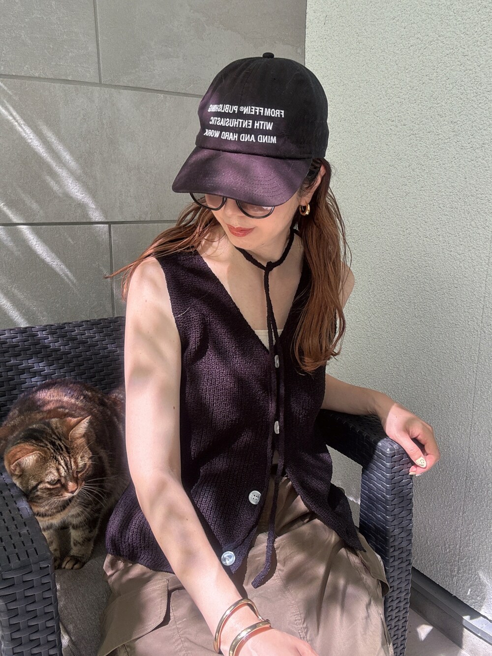 ブラック系のベスト、グリーン系のスカート、ブラック系のハンドバッグを着用したレディースの夏コーディネートの4枚目の写真