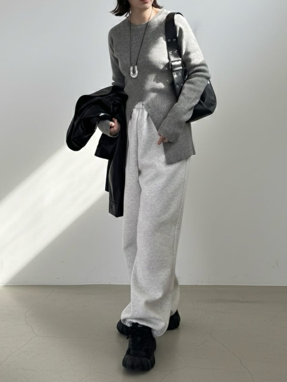 グレー系のニット/セーター、グレー系のスウェットパンツ、ブラック系のスニーカーを着用したレディースの冬コーディネートの3枚目の写真