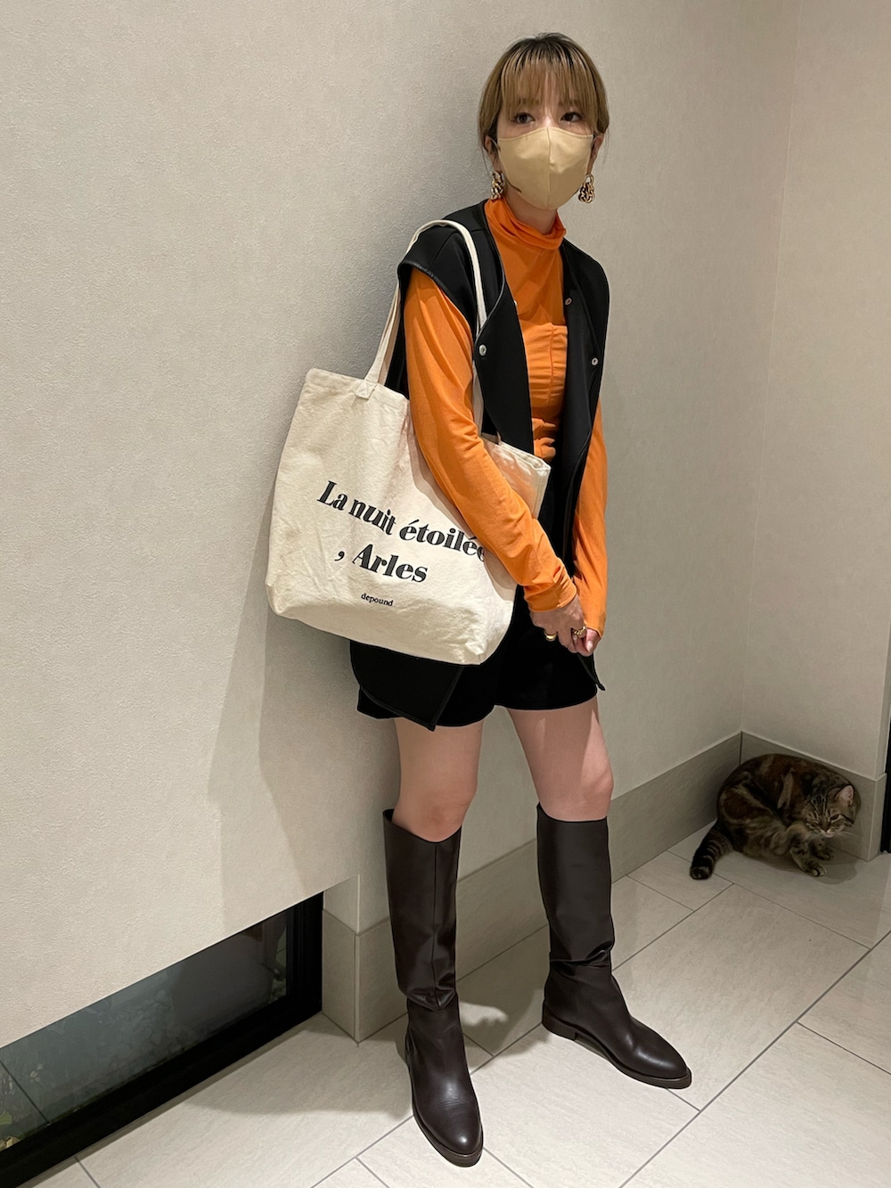 オレンジ系のTシャツ/カットソー、ブラック系のベスト、ブラウン系のブーツを着用したレディースの夏コーディネートの2枚目の写真