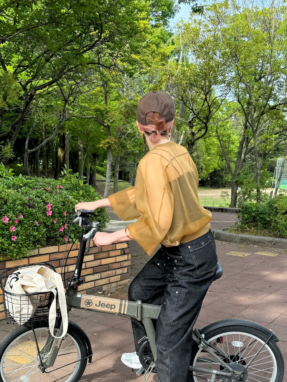 ブラック系のデニムパンツ、グレー系のスニーカー、ホワイト系のトートバッグを着用したレディースの春コーディネートの3枚目の写真
