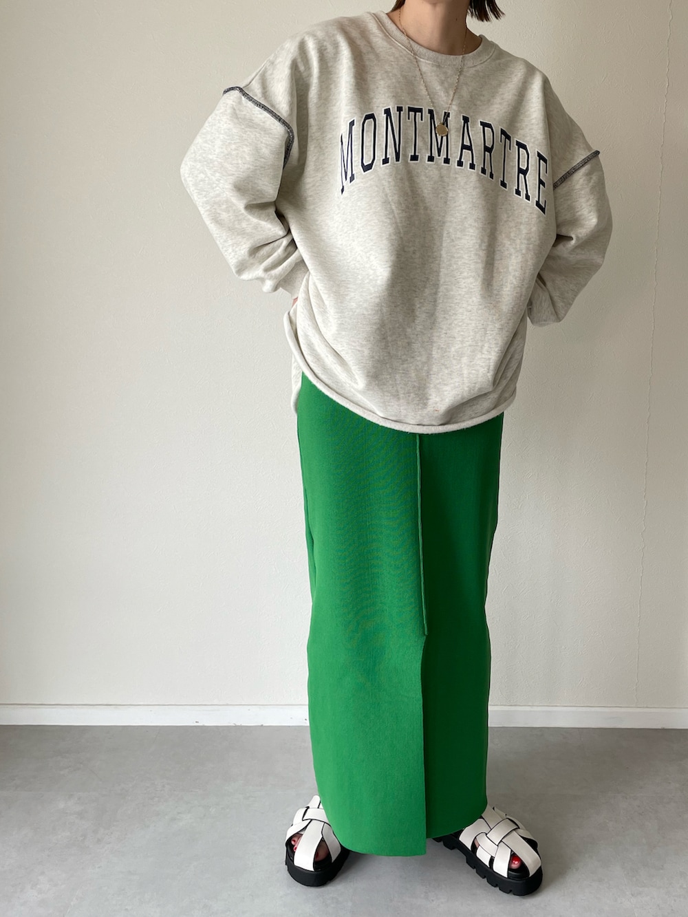 ホワイト系のサンダル、グリーン系のスカート、グレー系のスウェットを着用したレディースの春コーディネートの2枚目の写真