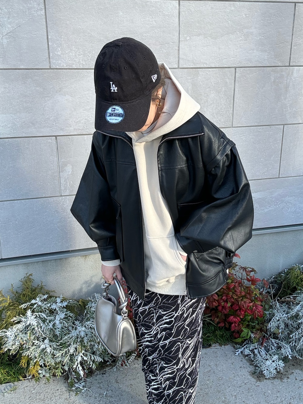 ブラック系のライダースジャケット、シルバー系のショルダーバッグ、ブラック系のスニーカーを着用したレディースの冬コーディネートの3枚目の写真