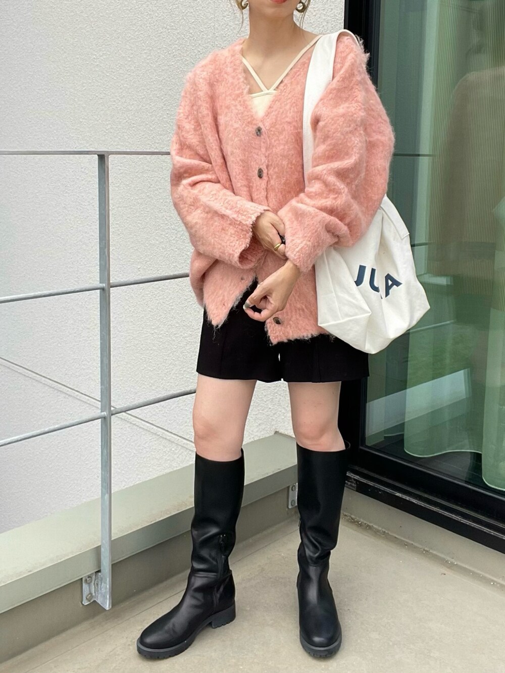 オレンジ系のニット/セーター、ブラック系のその他パンツ、ホワイト系のキャミソールを着用したレディースの秋コーディネートの4枚目の写真