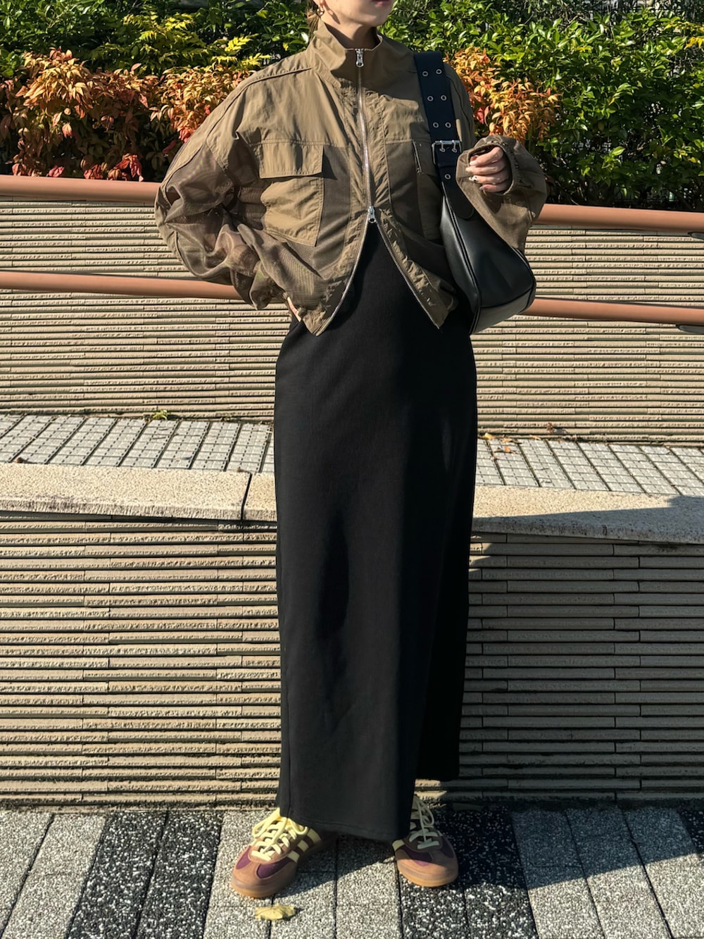 レッド系のスニーカー、ブラック系のハンドバッグ、ブラック系のワンピースを着用したレディースの秋コーディネートの2枚目の写真