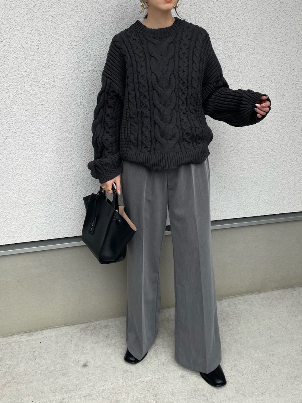 ブラック系のニット/セーター、ブラック系のハンドバッグを着用したレディースの秋コーディネートの2枚目の写真