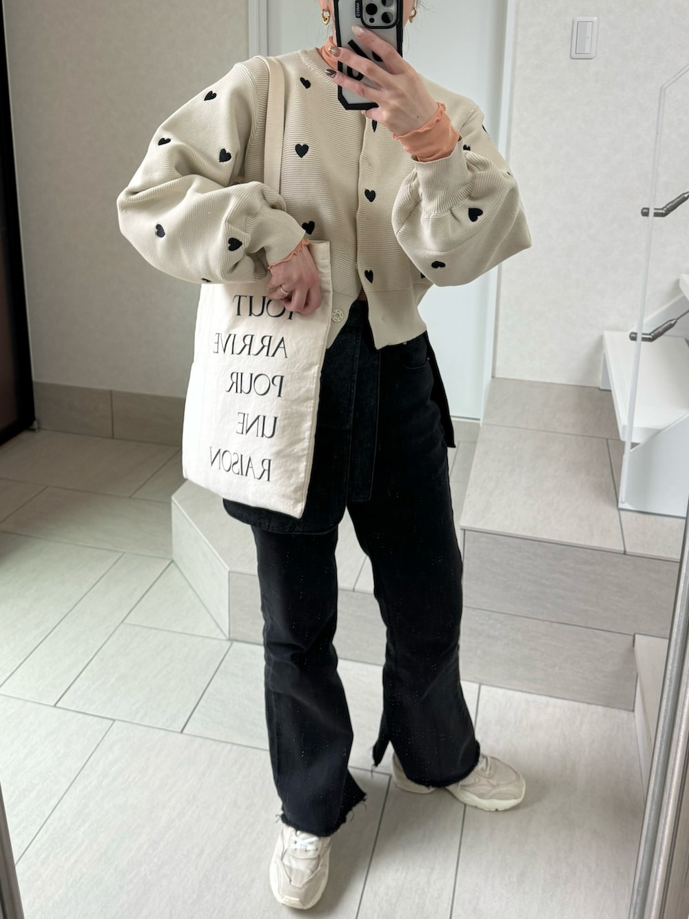 ベージュ系のカーディガン/ボレロ、ブラック系のデニムパンツ、オレンジ系のTシャツ/カットソーを着用したレディースの春コーディネートの5枚目の写真