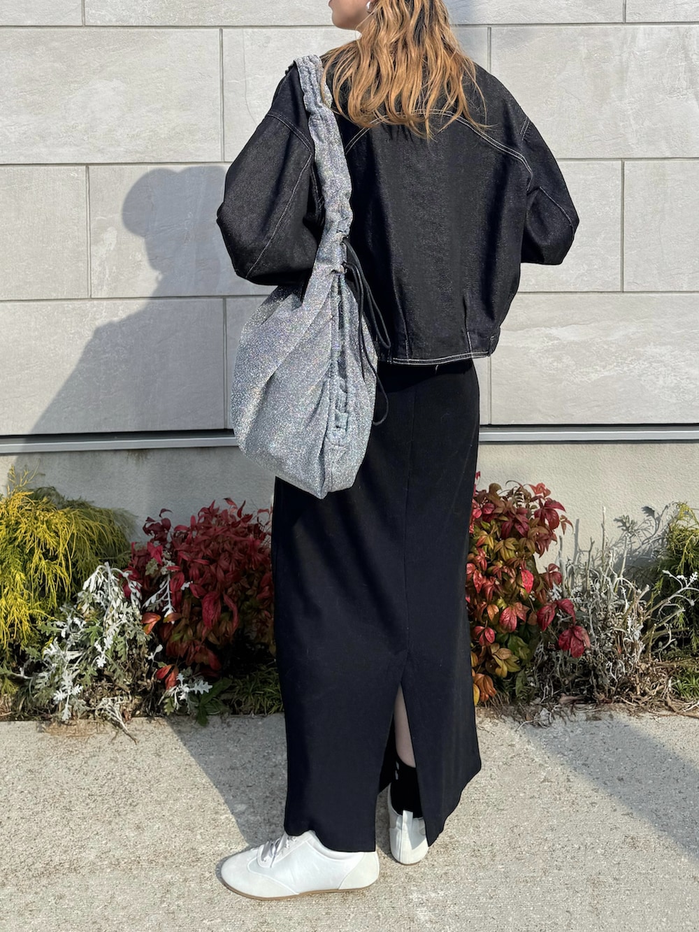 グレー系のスニーカー、ブラック系のワンピース、ブラック系のデニムジャケットを着用したレディースの春コーディネートの5枚目の写真