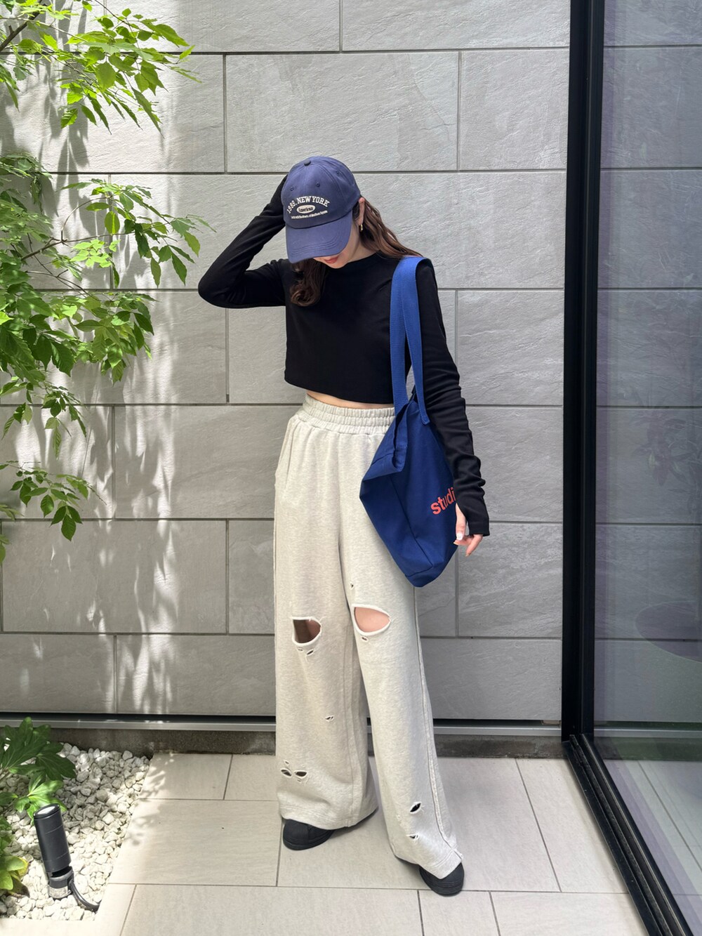 グレー系のスウェットパンツ、ブラック系のTシャツ/カットソー、ブラック系のスニーカーを着用したレディースの春コーディネートの2枚目の写真