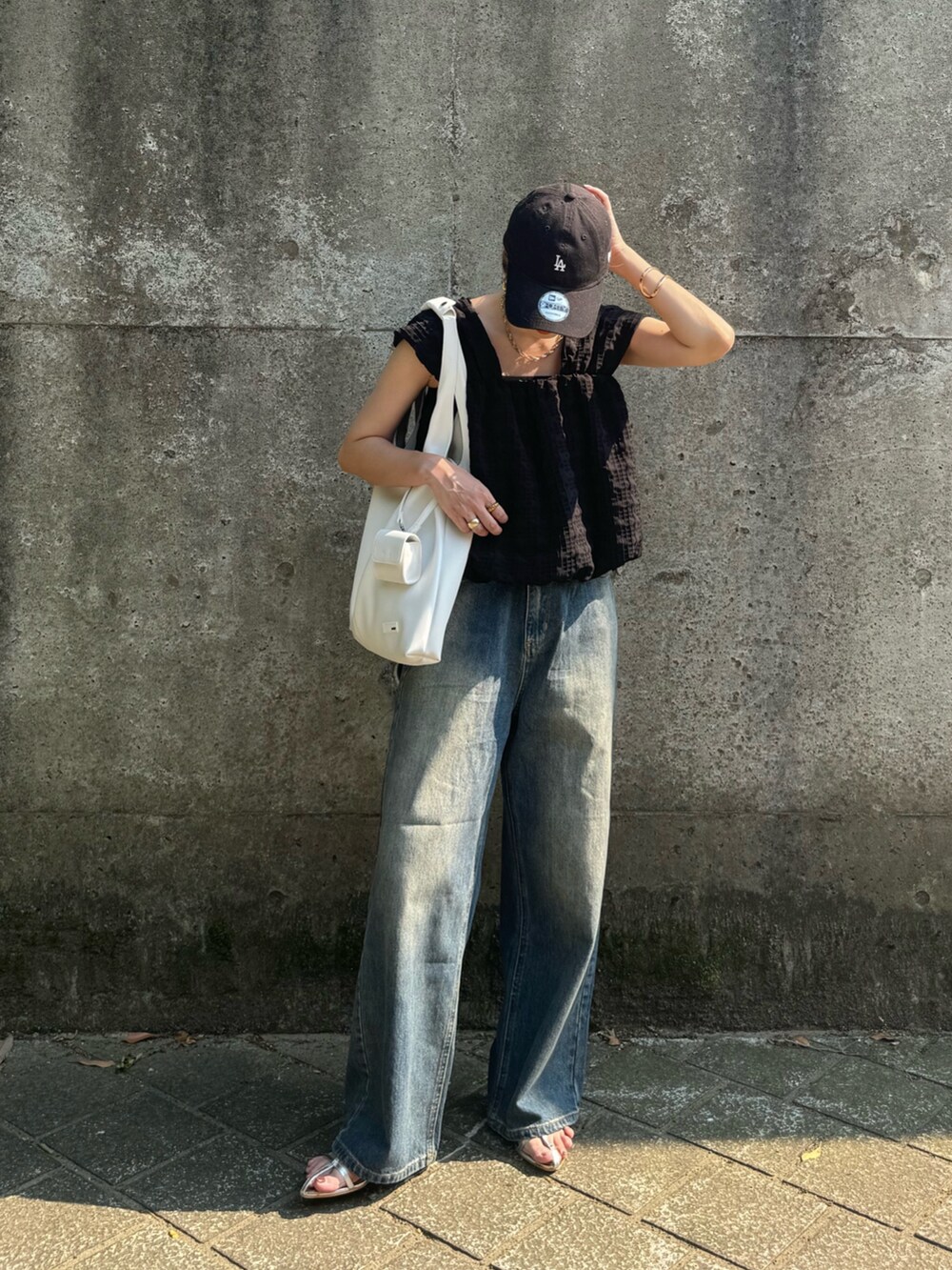 ホワイト系のトートバッグ、ブルー系のデニムパンツ、シルバー系のサンダルを着用したレディースの夏コーディネートの2枚目の写真