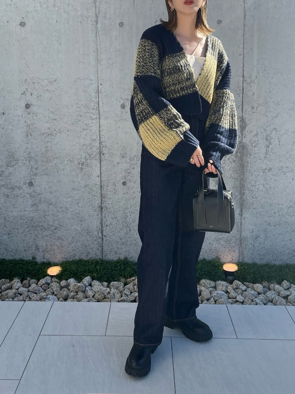 ブルー系のニット/セーター、ブラック系のボストンバッグ、ブルー系のデニムパンツを着用したレディースの秋コーディネートの2枚目の写真