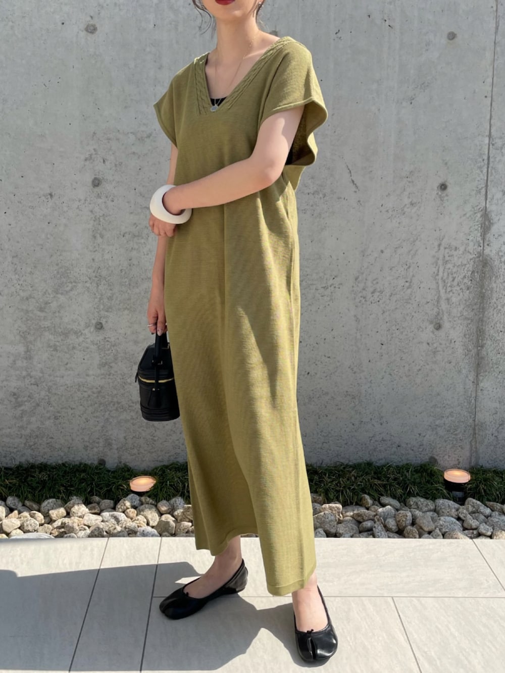 グリーン系のワンピース、ブラック系のパンプス、ホワイト系のブレスレットを着用したレディースの夏コーディネートの2枚目の写真