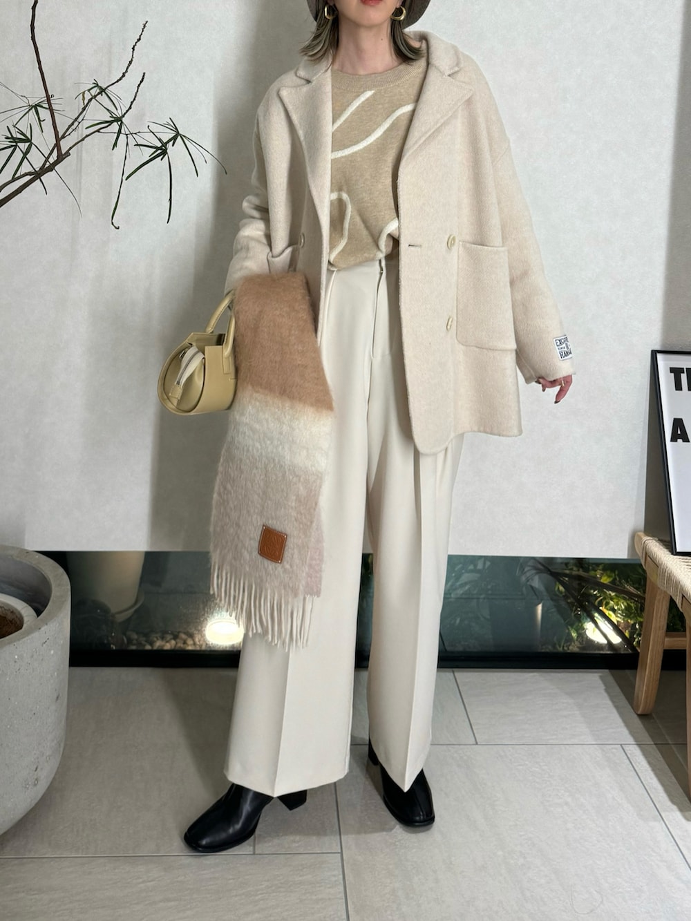 ベージュ系のニット/セーター、ホワイト系のその他パンツ、ベージュ系のハンドバッグを着用したレディースの冬コーディネートの3枚目の写真