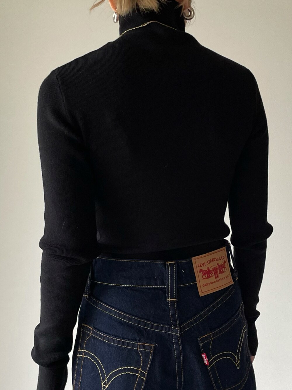 ブラック系のニット/セーター、ブルー系のデニムパンツ、ブラウン系のショルダーバッグを着用したレディースの冬コーディネートの3枚目の写真