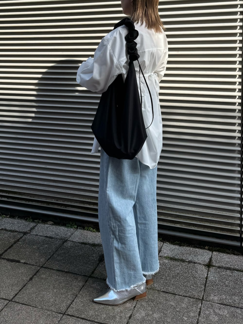 ホワイト系のシャツ/ブラウス、シルバー系のパンプス、ブルー系のデニムパンツを着用したレディースの冬コーディネートの3枚目の写真