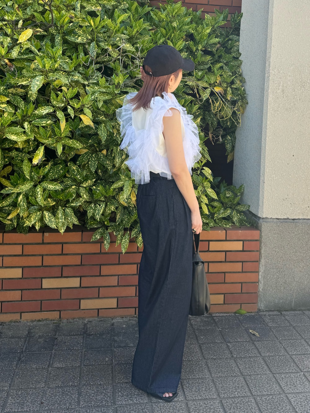 ブルー系のデニムパンツ、ホワイト系のタンクトップ、ブラック系のハンドバッグを着用したレディースの春コーディネートの4枚目の写真