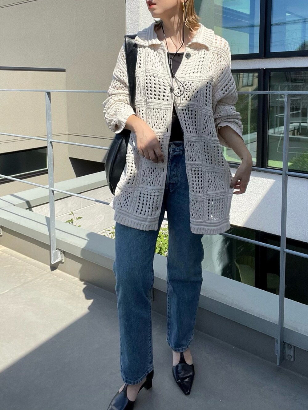 ブルー系のデニムパンツ、ホワイト系のカーディガン/ボレロ、ブラック系のパンプスを着用したレディースの秋コーディネートの2枚目の写真